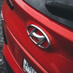 Close-up view of a red Hyundai car with a focus on the emblem and rear design.