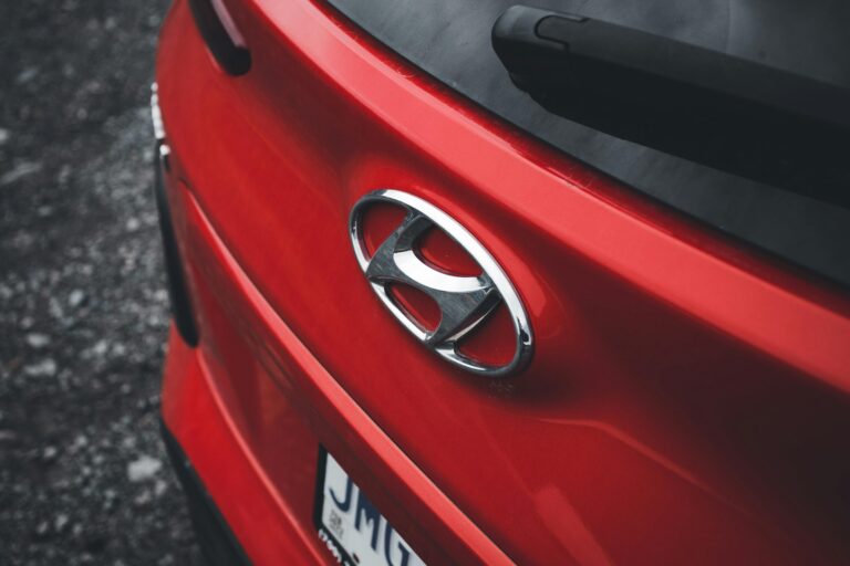 Close-up view of a red Hyundai car with a focus on the emblem and rear design.