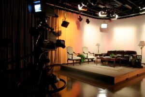 A studio setup featuring cameras and a green screen for production purposes.